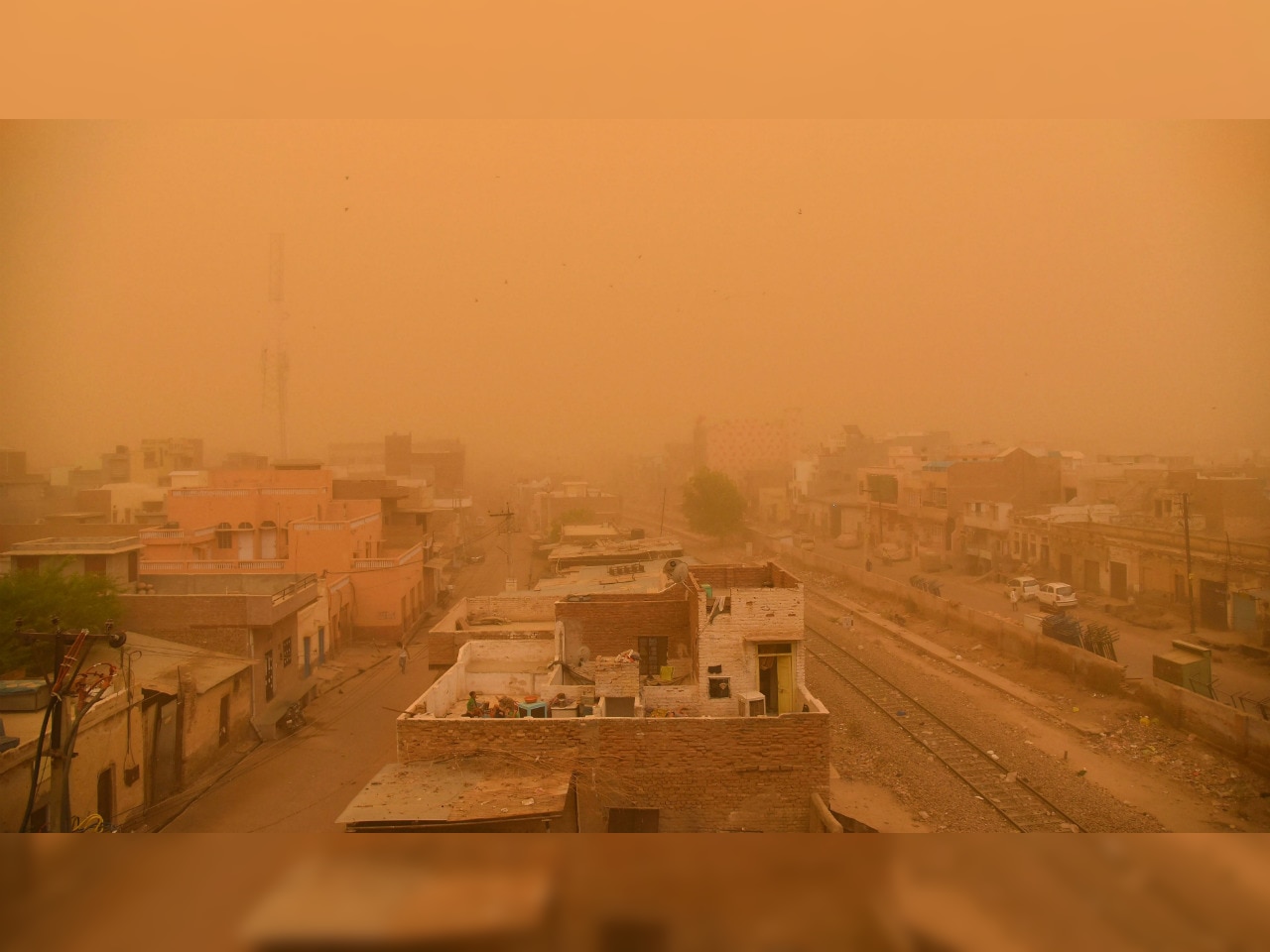 A severe orange dust storm covering buildings and railway tracks in Bikaner