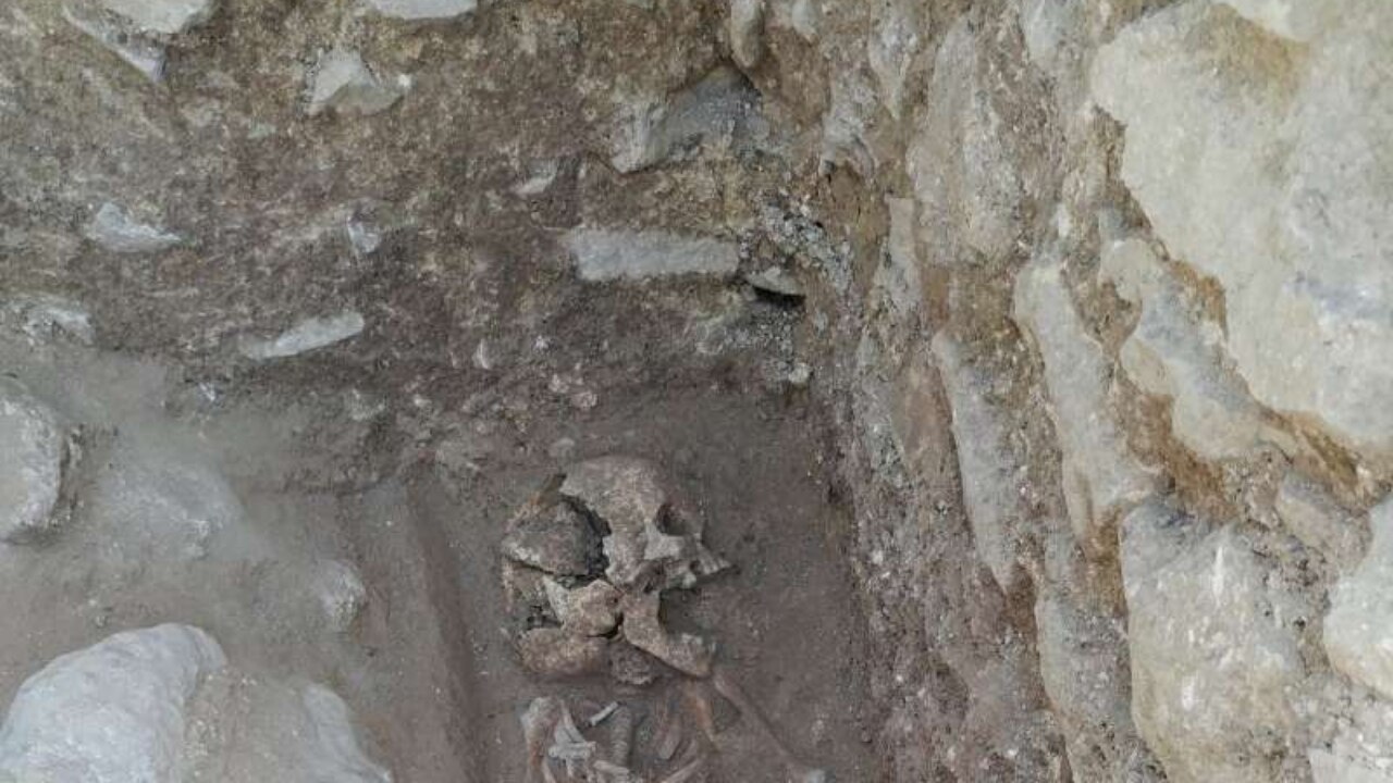  An image of an archaeological dig showing a human skeleton, believed to be a vampire, with a brick through its skull, consistent with vampire burial practices.