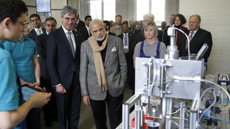 Indian Prime Minister Narendra Modi (C) and Siemens CEO Joe Kaeser (L), look at a 'coffee machine' build by trainees during a visit to the Siemens company in Berlin, on April 13, 2015. AFP.