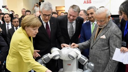 German Chancellor Angela Merkel (L) touches the collaborative dual-arm robot YuMi next to Indian Prime Minister Narendra Modi (2ndR) at the Swiss automation group ABB booth.