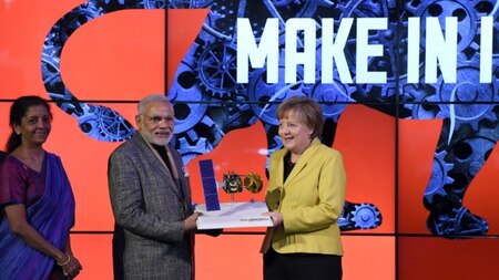 German Chancellor Angela Merkel (R) and Indian Prime Minister Narendra Modi (C) hold a model of the Mars Orbiter Mission spacecraft of the Indian Space Research Organisation.