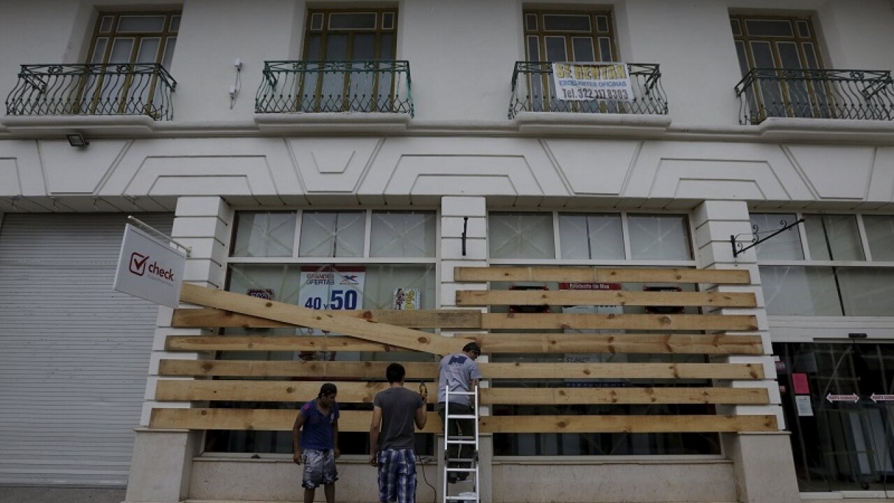 An employee boards up the windows of a store