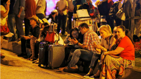 Evacuated passengers wait outside the airport