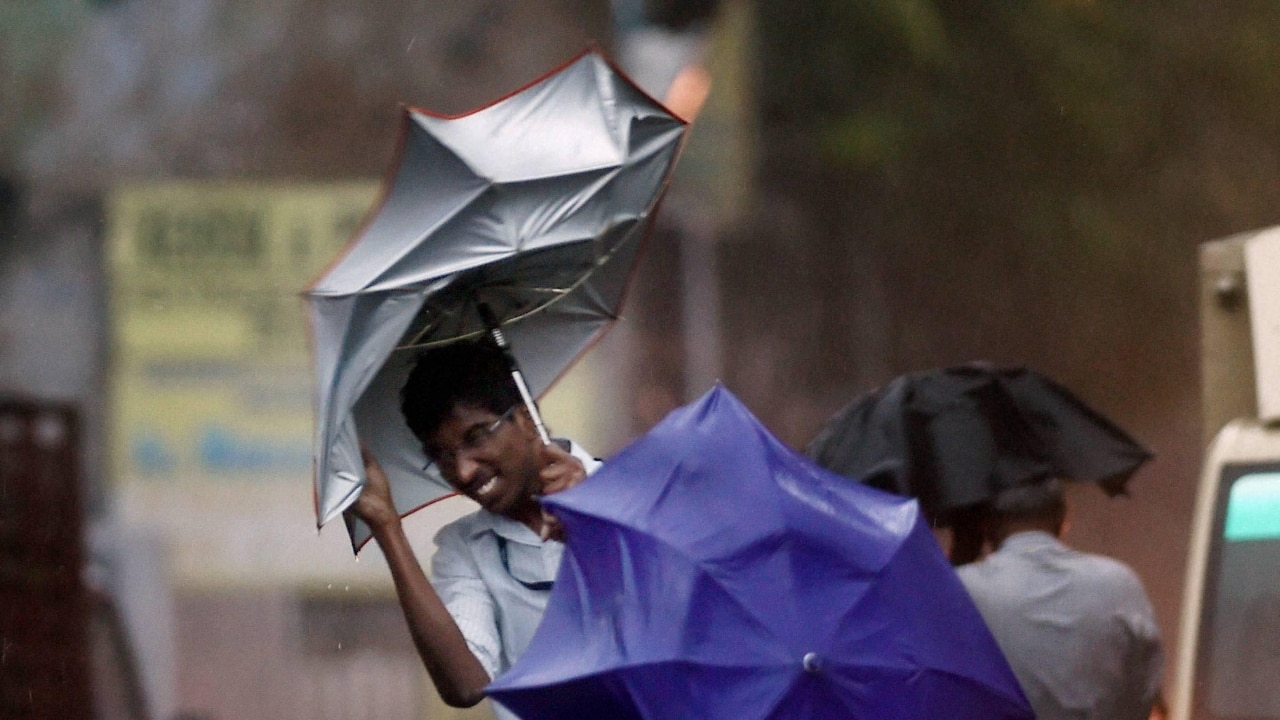 Man walking on road holding umbrellas during heavy rainfall