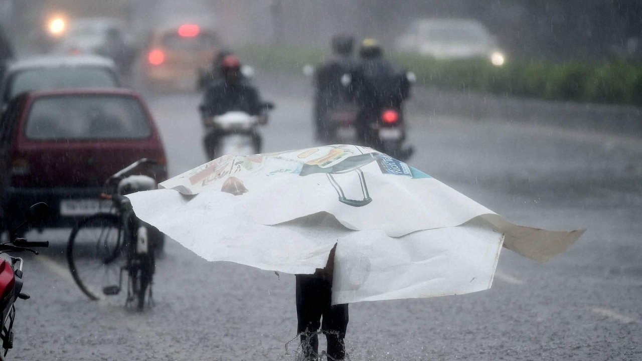 A person wades through road filled with water during heavy rainfall