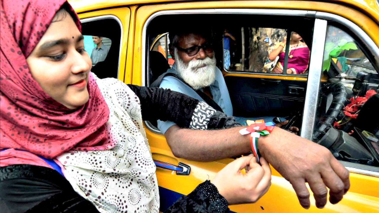 Woman tying rakhi to taxi driver