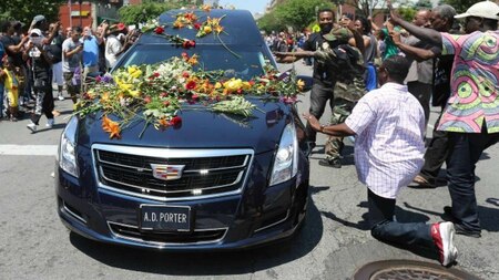 A man kneels down to the hearse in respect