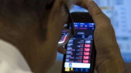 An investor monitors share prices on his mobile phone