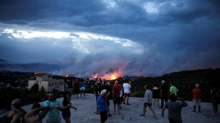 People watch a wildfire raging in the town of Rafina