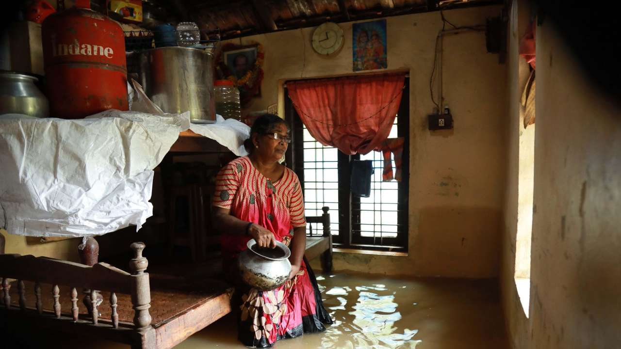 Woman sits inside her houses immersed in flood waters