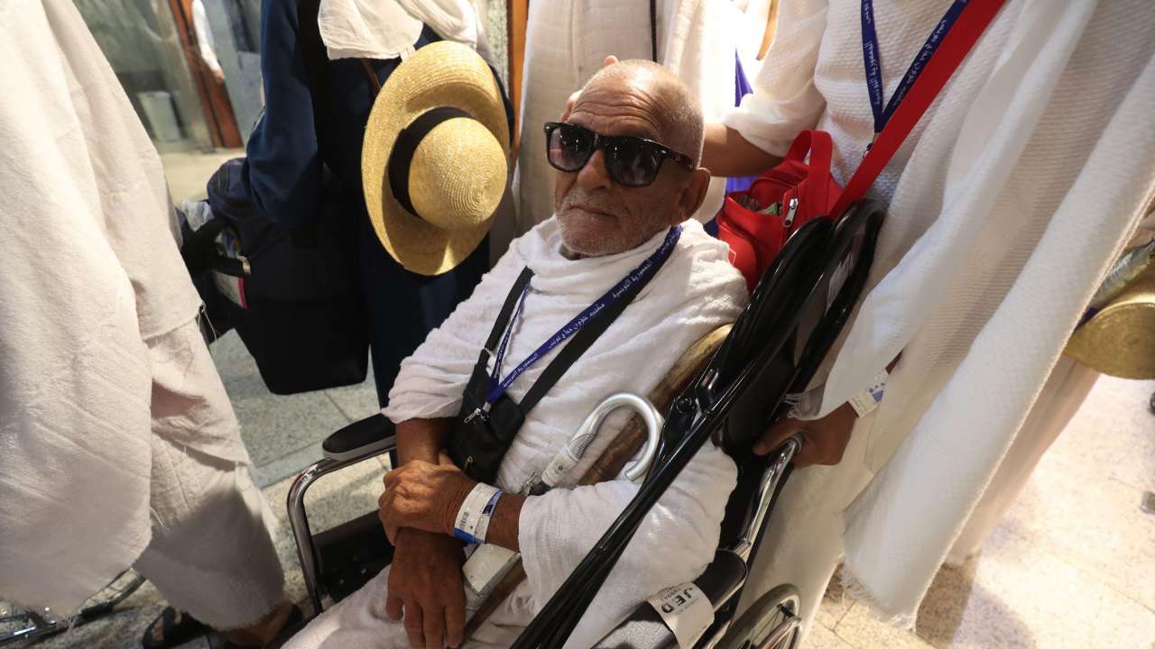 An old pilgrim prepares to board bus