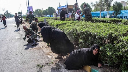 Iranian women and soldiers taking cover next to bushes
