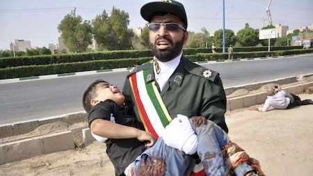 Revolutionary Guard member carries a wounded boy