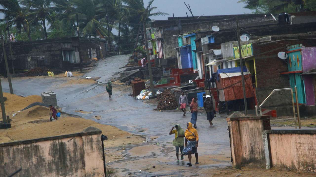 Ganjam: Locals walk near their houses as Cyclone Titli hits the coast, in Ganjam, Thursday, Oct 11, 2018. The 