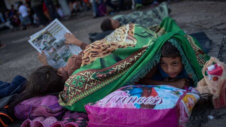 10-year-old boy peeks out of his blanket as he travels with caravan