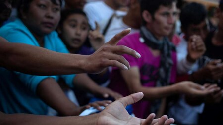 Migrants place their hands forward for food donations