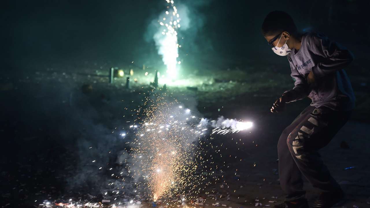 A child wearing a pollution mask bursting crackers