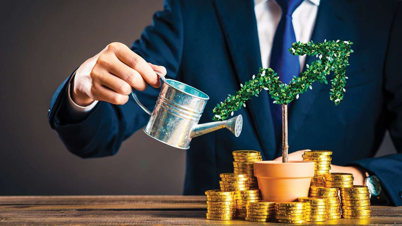  A businessman waters a plant growing out of a pile of gold coins, symbolizing the growth of wealth through hard work, financial management, and investing.