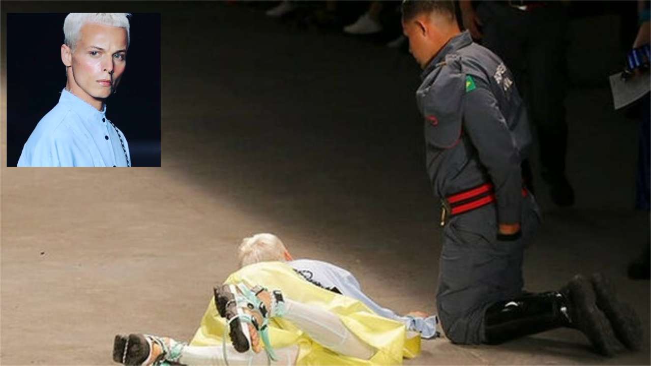 Model Tales Soares lies on the catwalk as a paramedic tends to him