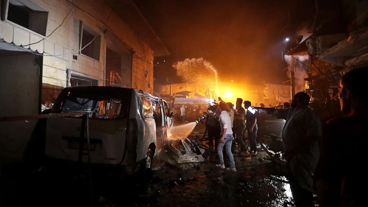 People try to extinguish a fire at the site of a car bomb blast in Azaz, Syria