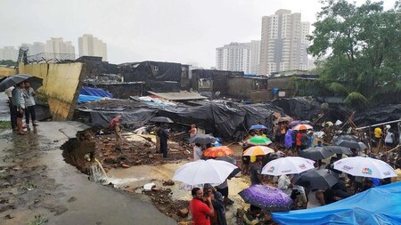 People look at debris after a wall collapsed in Mumbai's Malad