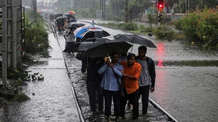 Commuters walk on waterlogged railway tracks in Mumbai