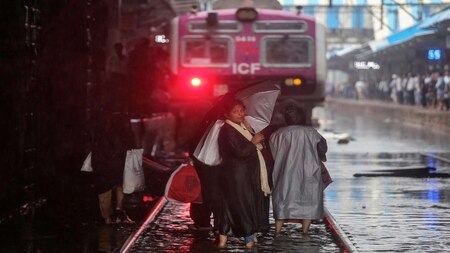 Commuters cross waterlogged railway tracks in Mumbai
