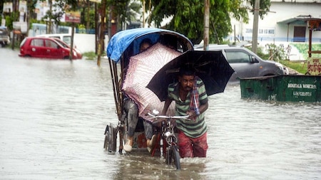 Rickshaw puller carries a commuter through flooded street