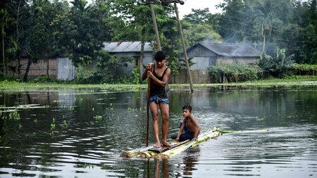 Children paddle a raft through floodwaters