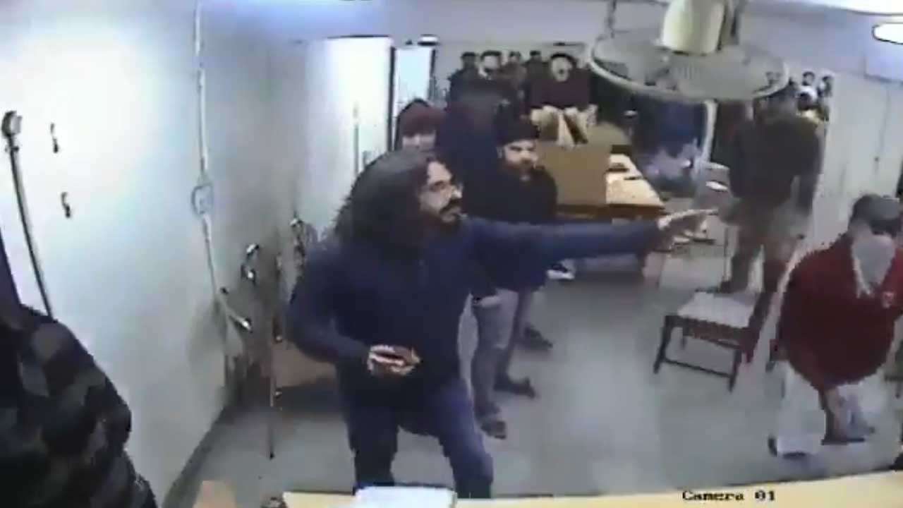 A screengrab from the video that shows a man with stone in hand and another with his face covered