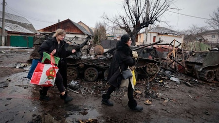 Bucha: Women walk past the remains of Russian military vehicles