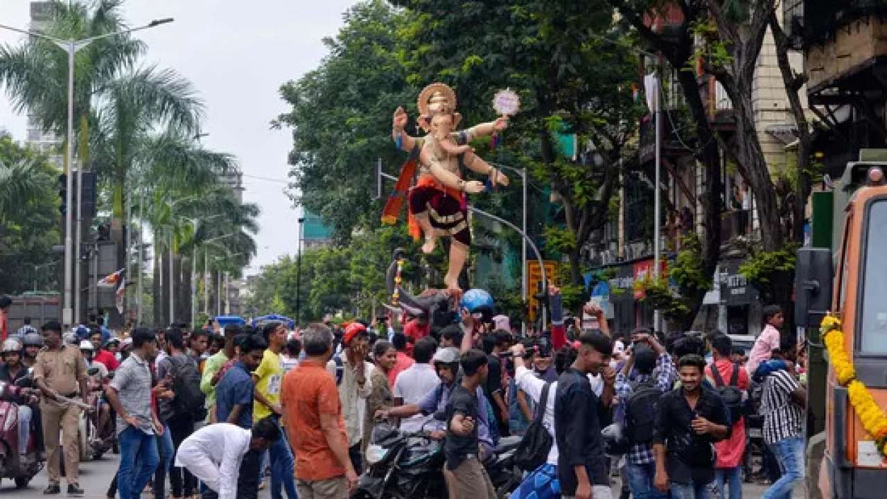 Devotees walk alongside an idol through street in Mumbai